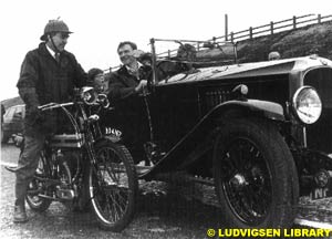 Morgan at the wheel of his vintage Vauxhall, with Mario Illien as passenger, chatting to a local English machine-shop owner