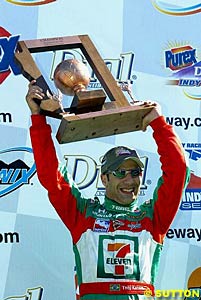 Tony Kanaan holds the winner's trophy aloft after taking his first IRL victory