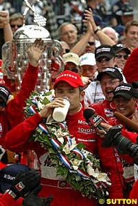 Gil de Ferran drinks the traditional bottle of milk after winning the Indianapolis 500