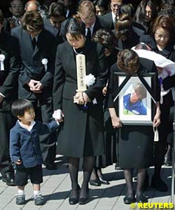 Two year old Ikko holds his mother Makiko's hand during the funeral service for his father, Japanese MotoGP rider Daijiro Kato, as the rider's mother Hatsumi holds his portrait at Tokyo's Kanei-ji Temple