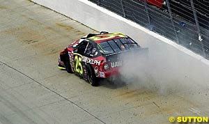 Joe Nemechek's wrecked car slides along the fence after literally knocking a hole in the wall