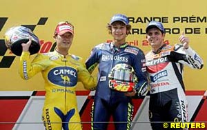 Second place finisher Makoto Tamada, winner Valentino Rossi and third place finisher Alex Barros celebrate on the podium